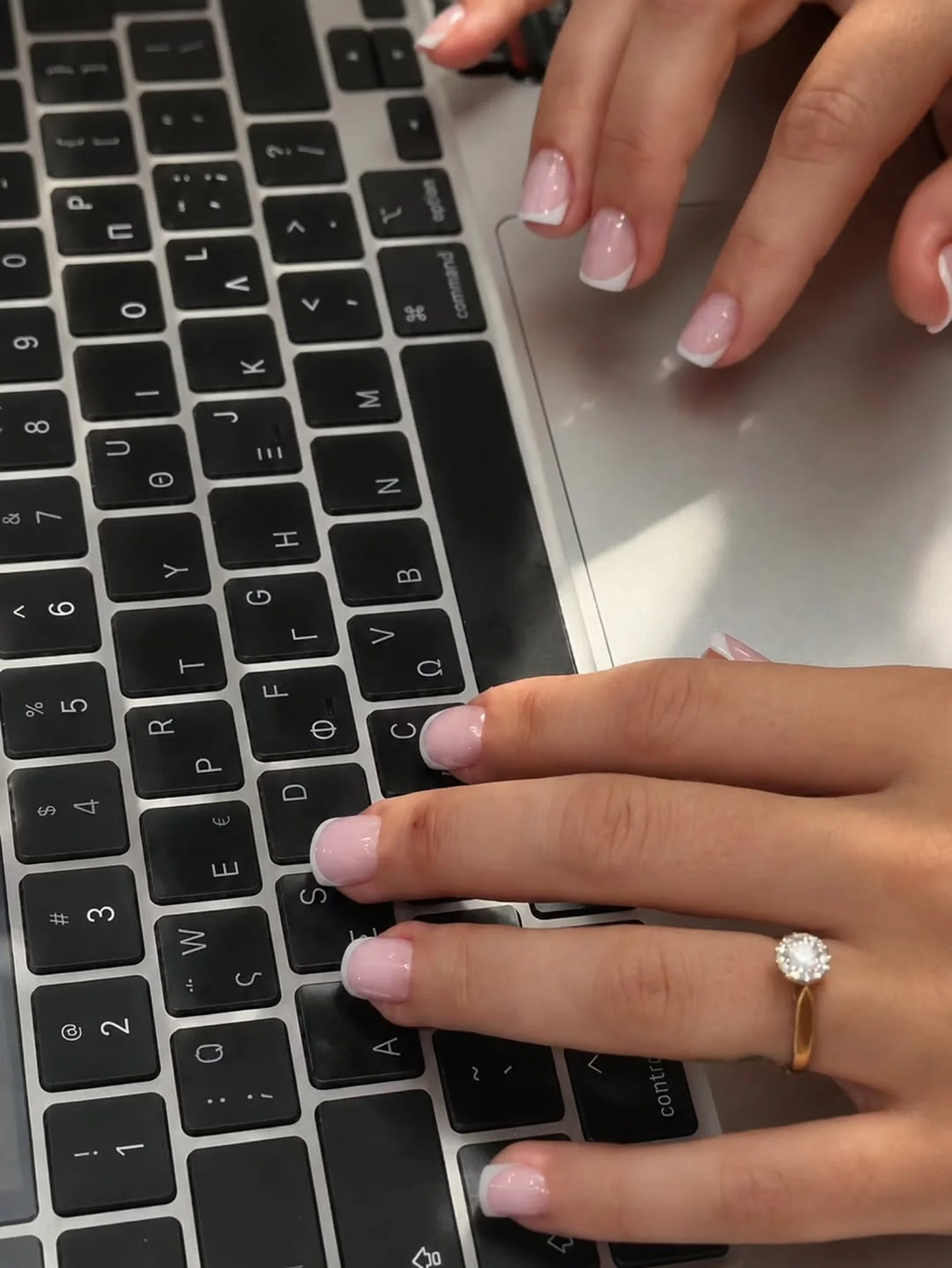 Fresh soft pink nails typing on a laptop